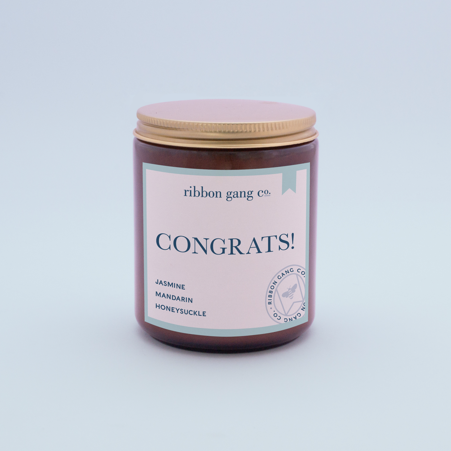 Congrats candle in an amber jar with gold lid screwed on.