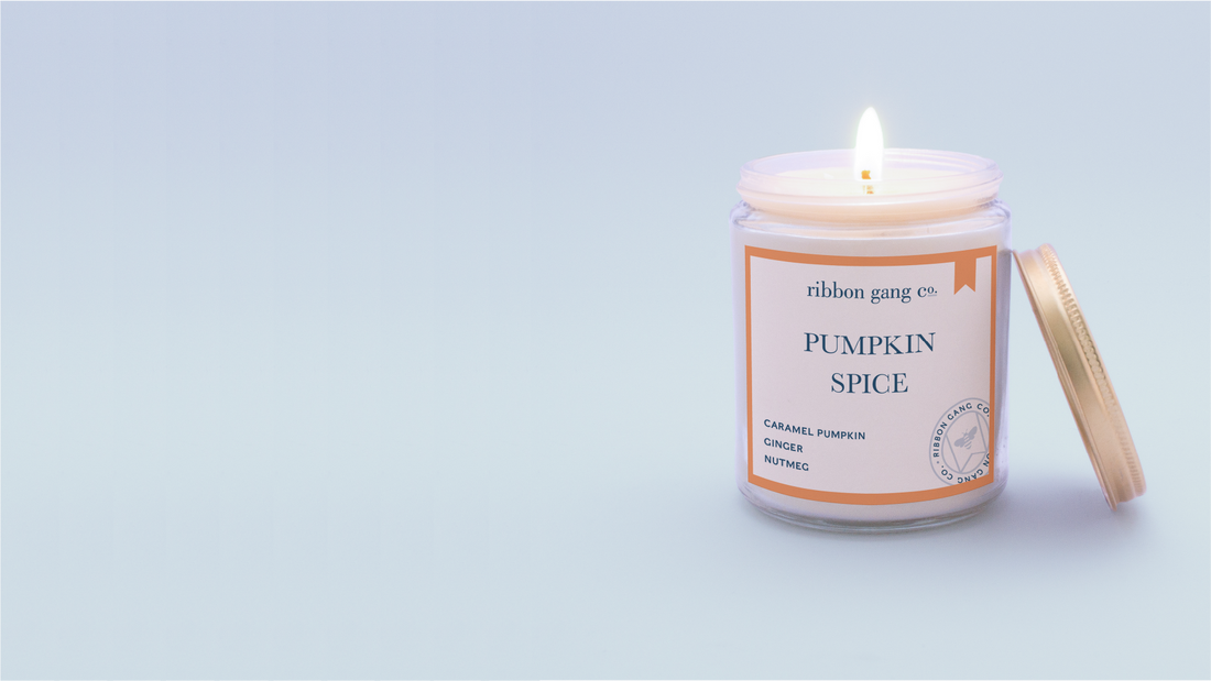 Pumpkin Spice scented candle burning on a blue background.