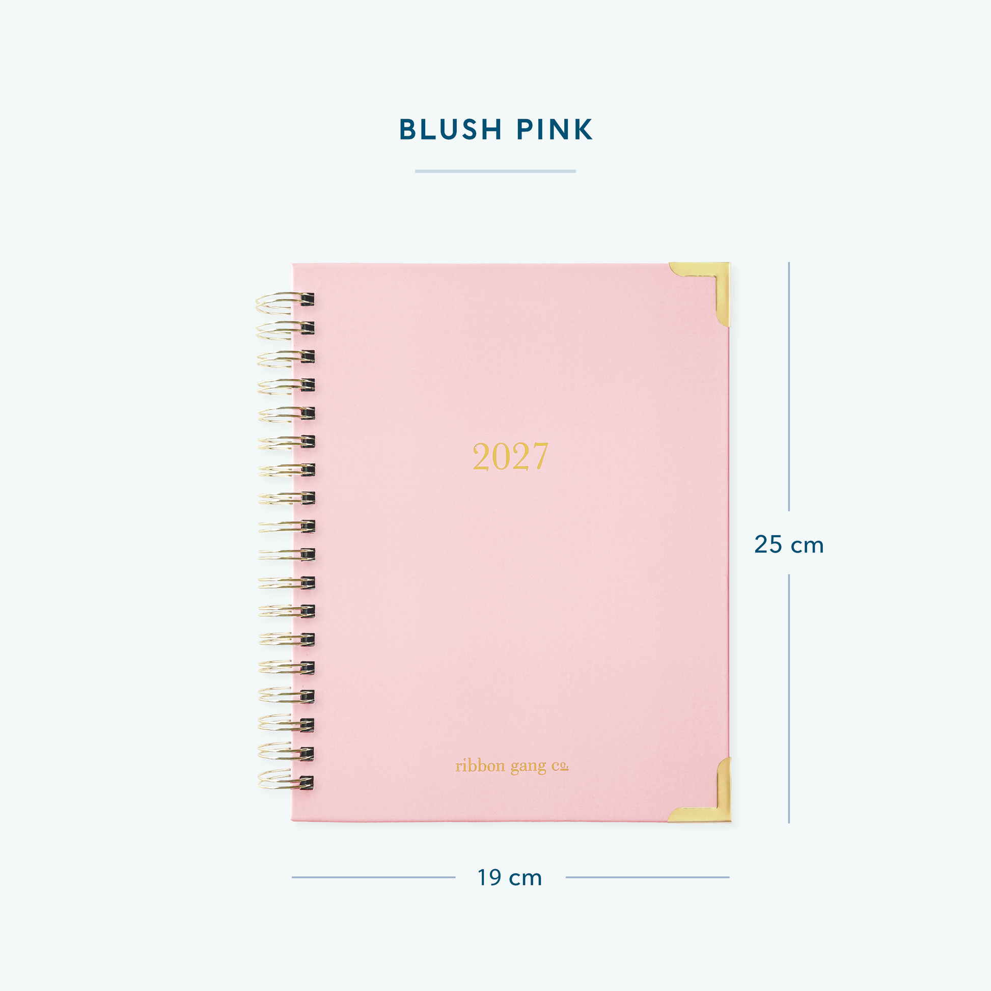 A blush pink spiral bound 2027 planner with gold lettering and gold corners on a white background showing dimensions of 25 cm high and 19 cm wide.