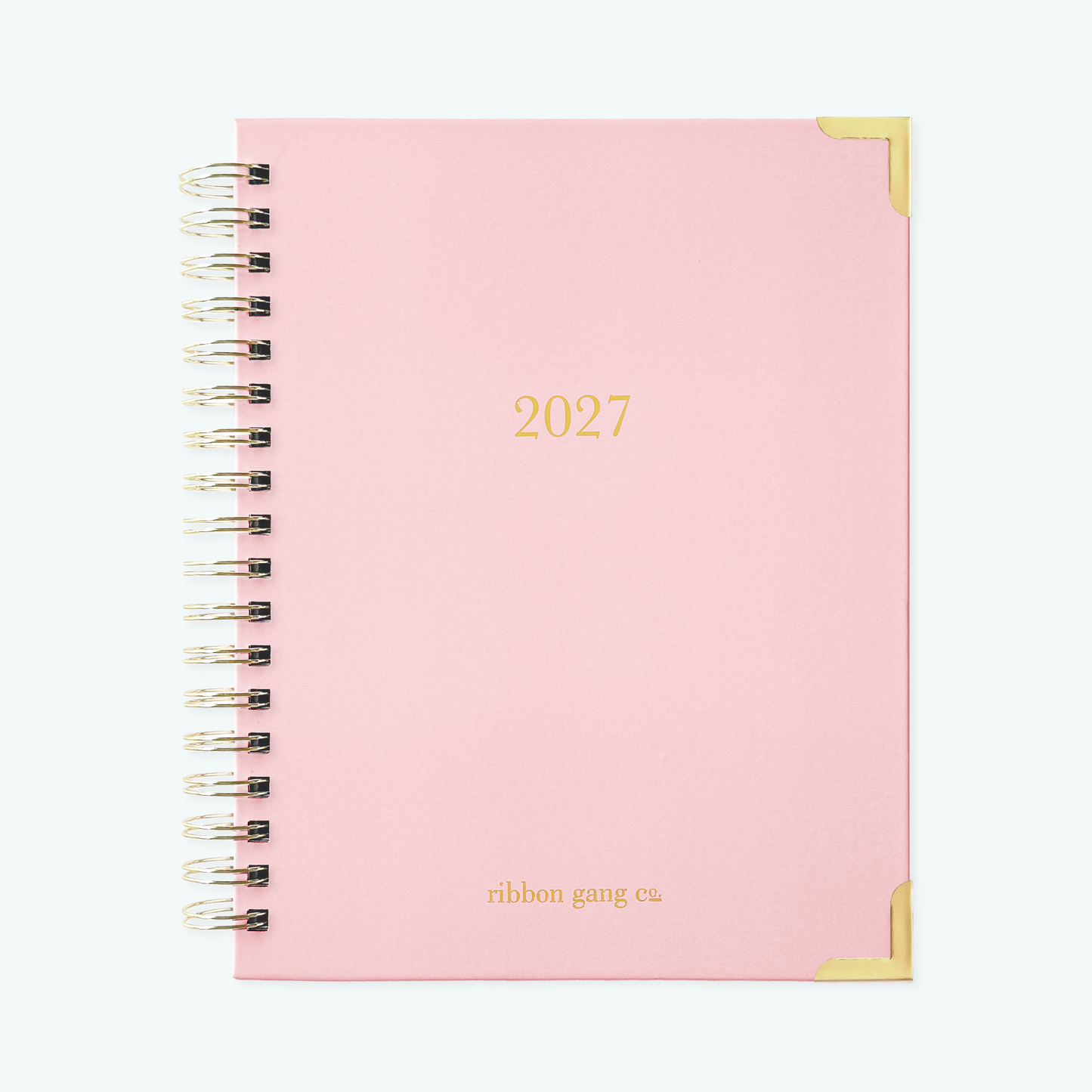 A blush pink spiral bound 2027 planner with gold lettering and gold corners on a white background.