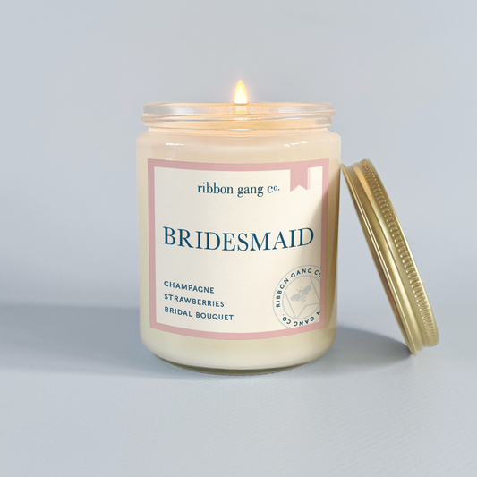 Bridesmaid candle with 'ribbon gang co.' label on a gray background.