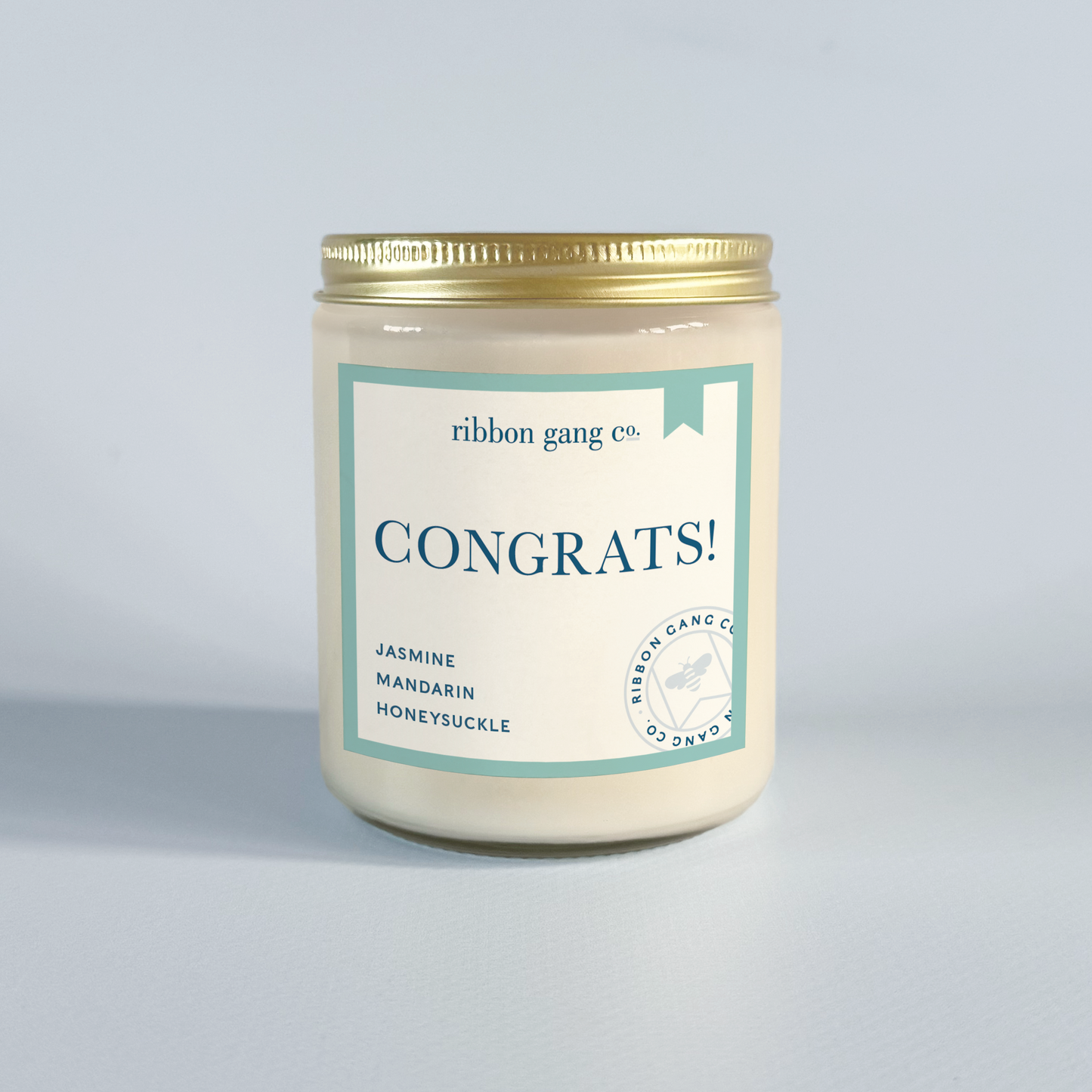 Candle jar with 'Congrats!' label by Ribbon Gang Co. on a light grey background.