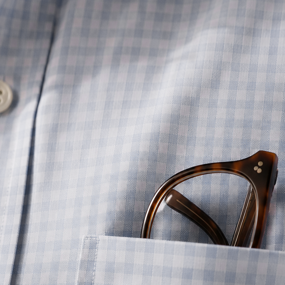 A man's check shirt with brown rimmed glasses in the pocket.