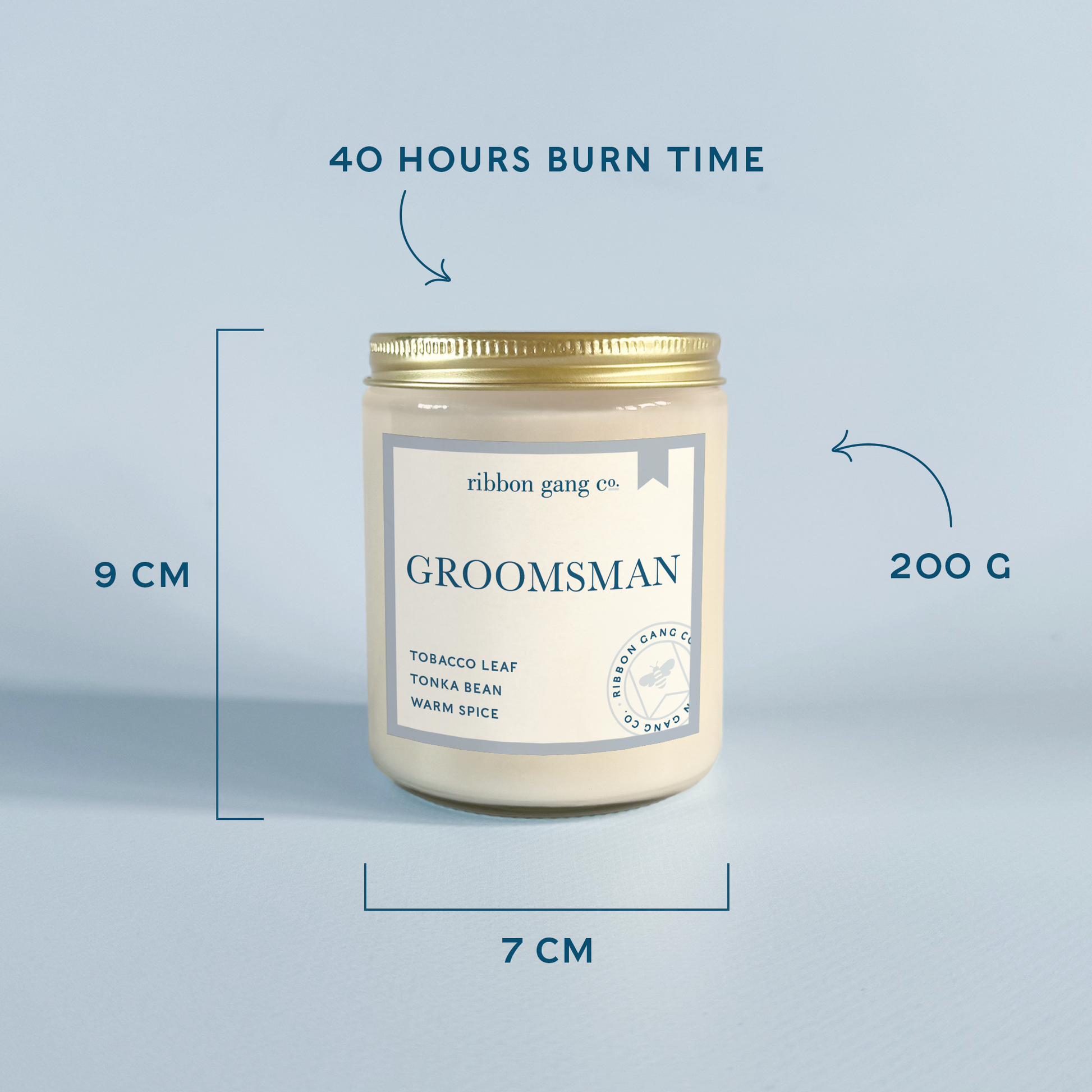 A candle jar labeled 'GROOMSMAN' with text callouts showing dimensions: 9 cm height, 7 cm width, and 200 g weight, plus '40 HOURS BURN TIME' above. The candle is in a clear glass jar with cream wax, a gold lid, and a pale blue-and-white label on a light blue background.