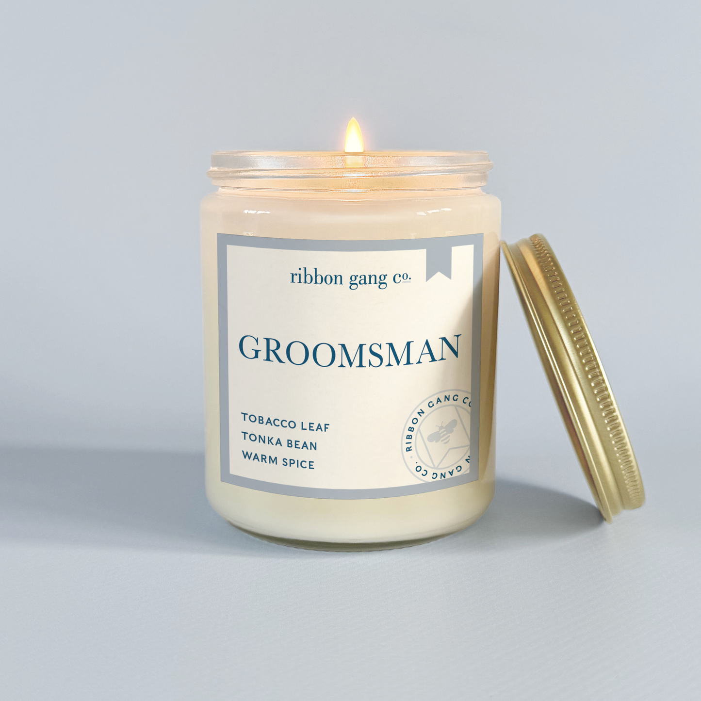 Candle in a jar labeled 'Groomsman' by Ribbon Gang Co. on a light gray background.