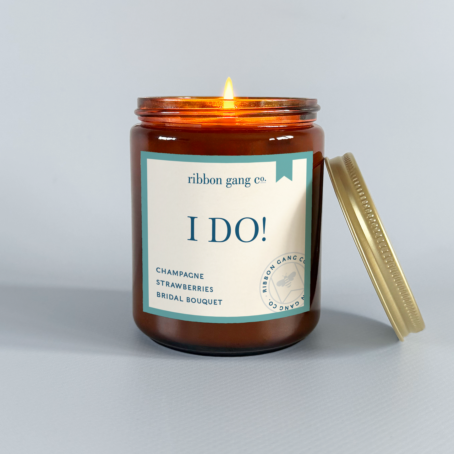Candle in an amber jar with a label on a grey background.