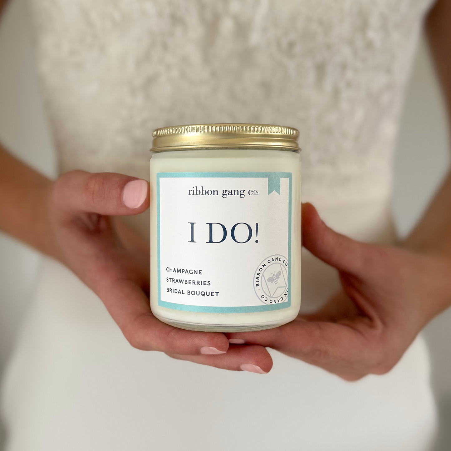 Person holding a candle jar labeled 'I DO!' by Ribbon Gang Co.