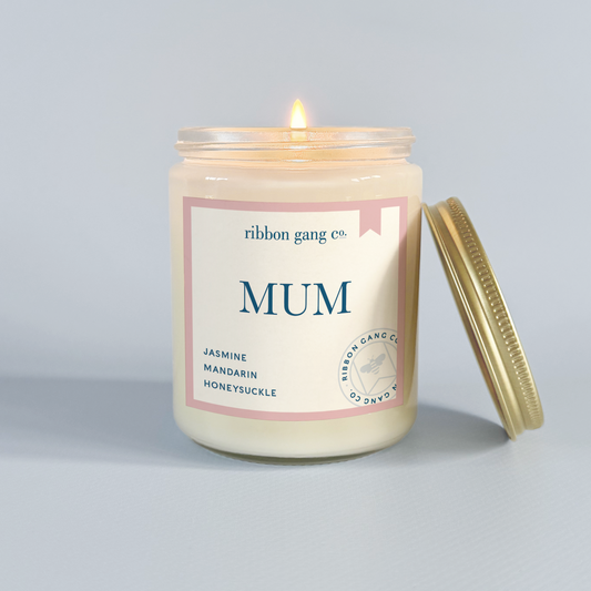 Candle with 'MUM' label from Ribbon Gang Co. on a light grey background.