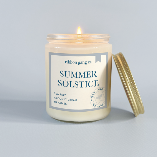 Candle labeled 'Summer Solstice' by Ribbon Gang Co. on a light grey background.